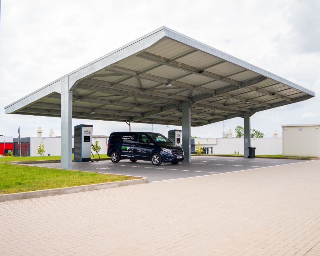 Solarcarport mit Ladestation für Elektrofahrzeuge auf einem modernen Firmenparkplatz.